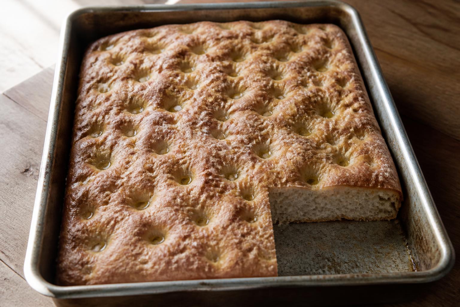 Fertig gebackene Focaccia Genovese im Blech mit Olivenöl in den Fingerkuhlen und offener Krume